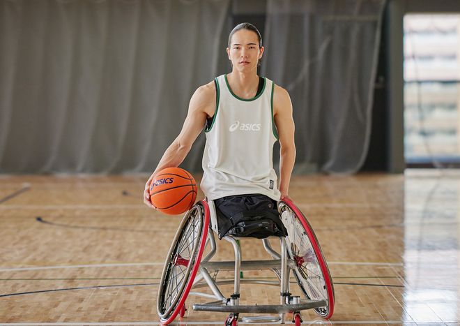 鳥海連志選手が体育館でバスケットゴールを背に車椅子に乗りボールを持っている写真