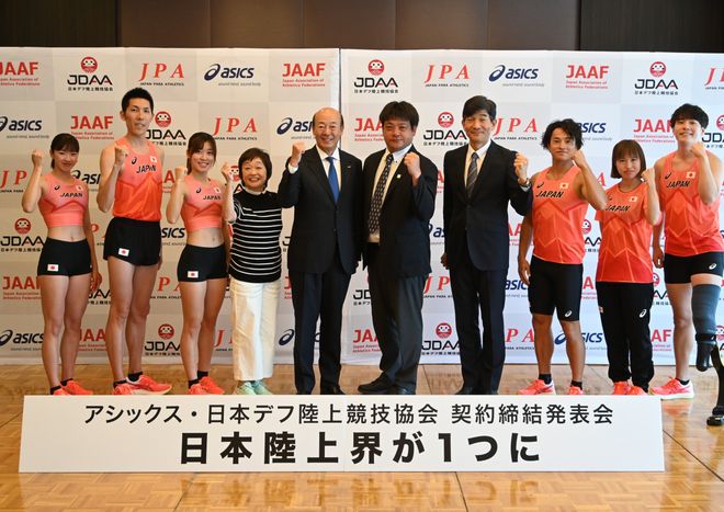 計画記者会見場で「日本陸上界がひとつに」の看板を前にガッツポーズをするアシックス廣田会長、増田明美さん、JDAA役員とアスリート、JPA役員とアスリート、計10名が並んだ写真